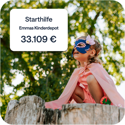 Mädchen mit Umhang und Augenmaske sitzt draußen auf einem Baumstamm; Einblendung: Starthilfe – Emmas Kinderdepot – 33.109 €