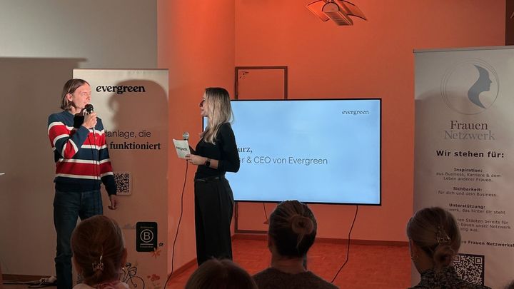 Iven Kurz spricht auf der Bühne der Female Finance Night, rechts das Banner des Frauen Netzwerks.