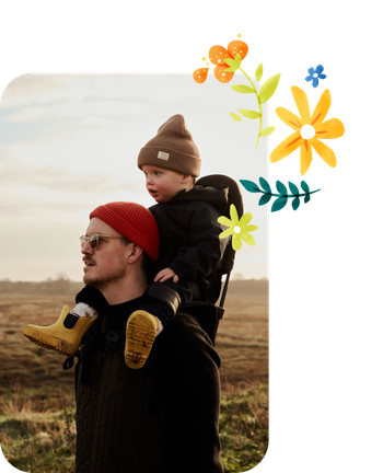 Ein Vater trägt seinen Sohn auf den Schultern durch die Natur.