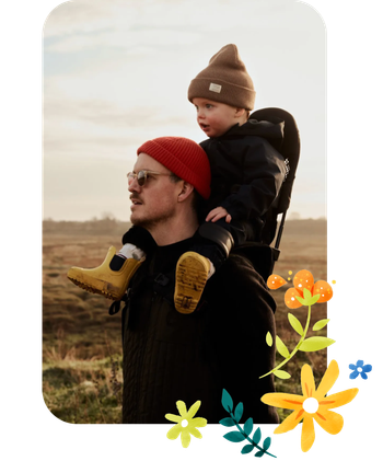 Ein Vater trägt seinen Sohn auf den Schultern durch die Natur.